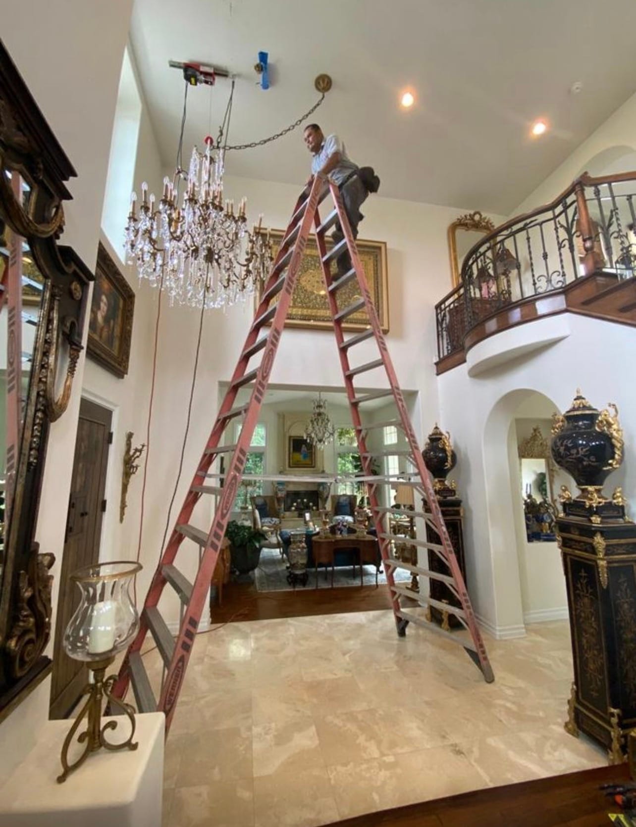 Crystal chandelier installation in a two-story foyer