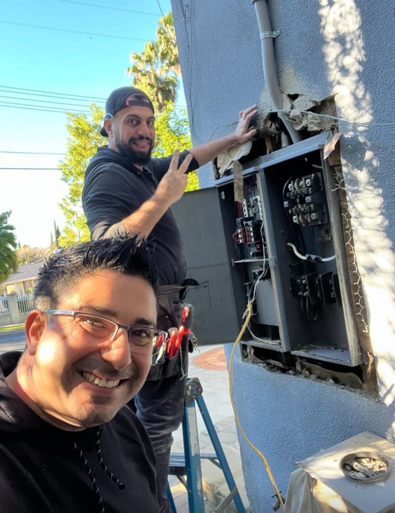 Two technicians at an open panel during a service upgrade
