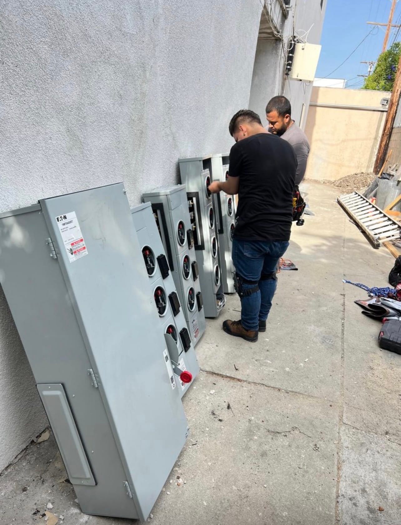 Two technicians installing a bank of commercial disconnects