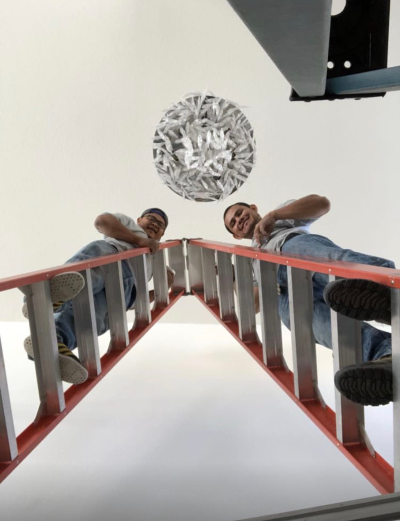 Two technicians installing a modern pendant light fixture